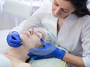 Kosmetolog má označenie žena zrelý pred z blízka selektívny sústrediť. kozmetický chirurgia postup 