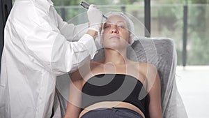 Cosmetologist doing hydrafacial treatment on woman face For rejuvenation