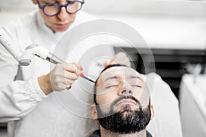 Cosmetologist doing laser facelifting procedure in beauty clinic