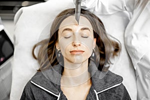Cosmetologist doing laser facelifting procedure in beauty clinic