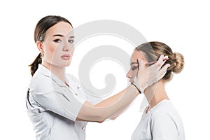 A cosmetologist examines the patient face and plans to perform a series of cosmetic procedures