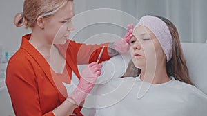 cosmetologist examining woman face before botox and fillers injection in beauty clinic