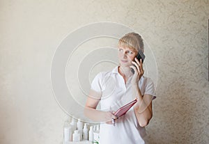 a cosmetologist girl consults a client by phone. pre-registration photo