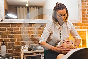 Cosmetologist giving a face lifting massage to her client in modern beauty spa