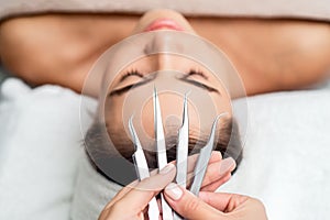 Cosmetologist holds tweezers for eyelash extensions