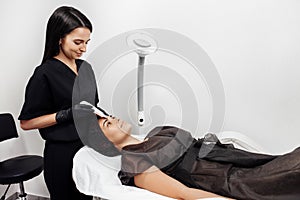 Cosmetologist make face while procedure ultrasound cavitation or facial peeling in cosmetology cabinet.