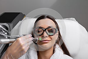 Cosmetologist make laser hair removal on woman& x27;s face