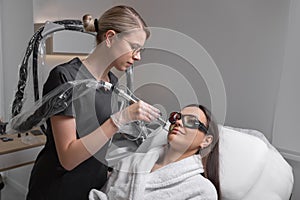 Cosmetologist make laser hair removal on woman& x27;s face