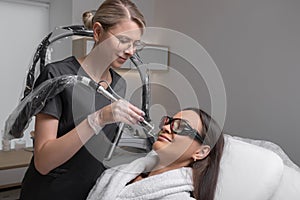 Cosmetologist make laser hair removal on woman& x27;s face