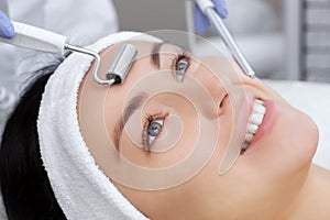 The cosmetologist makes the apparatus a procedure of Microcurrent therapy of a beautiful, young woman in a beauty salon