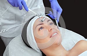 The cosmetologist makes the apparatus a procedure of Microcurrent therapy photo