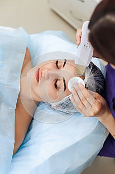 The cosmetologist makes the apparatus a procedure of ultrasound cleaning of skin