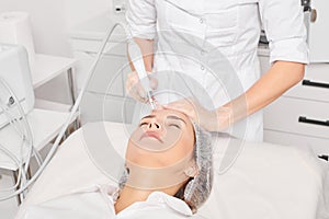 Cosmetologist makes aqua exfoliation for rejuvenation woman face skincare, procedure in beauty salon