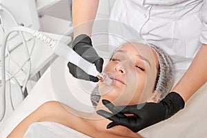 Cosmetologist makes aqua exfoliation for rejuvenation woman face skincare, procedure in beauty salon