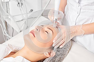 Cosmetologist makes aqua exfoliation for rejuvenation woman face skincare, procedure in beauty salon