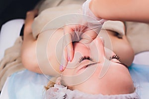 Cosmetologist makes a buccal massage of the patient`s facial muscles. photo