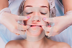 Cosmetologist makes a buccal massage of the patient`s facial muscles. photo