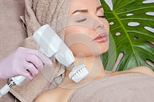 The cosmetologist makes the Hardware face cleaning  procedure with a soft rotating brush of a beautiful, young woman in a beauty