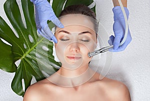 The cosmetologist makes the  Microdermabrasion procedure of the facial skin of a woman in a beauty salon.Cosmetology and