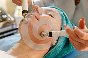 Cosmetologist makes the procedure microcurrent therapy in a beauty salon