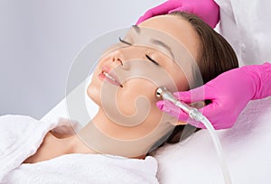 The cosmetologist makes the procedure Microdermabrasion of the face skin of a beautiful girl in a beauty salon.Cosmetology and