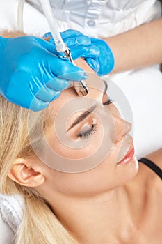 The cosmetologist makes the procedure Microdermabrasion of the face skin of a beautiful girl in a beauty salon.Cosmetology and