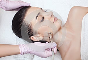 The cosmetologist makes the procedure Microdermabrasion of the face skin of a beautiful woman in a beauty salon.Cosmetology and