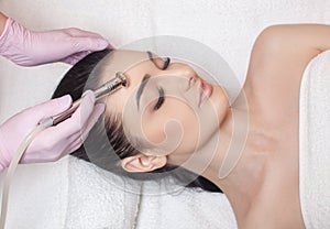 The cosmetologist makes the procedure Microdermabrasion of the face skin of a beautiful woman in a beauty salon.Cosmetology and
