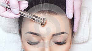 The cosmetologist makes the procedure Microdermabrasion of the face skin of a beautiful woman in a beauty salon.Cosmetology and