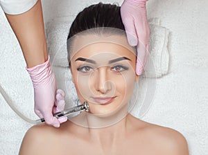 The cosmetologist makes the procedure Microdermabrasion of the face skin of a beautiful woman in a beauty salon.Cosmetology and