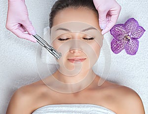 The cosmetologist makes the procedure Microdermabrasion of the face skin of a beautiful woman in a beauty salon.Cosmetology and