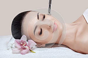 The cosmetologist makes the procedure Microdermabrasion of the facial skin of a beautiful, young woman