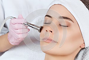 The cosmetologist makes the procedure Microdermabrasion of the facial skin of a beautiful, young woman