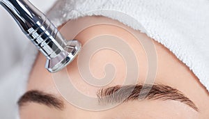 The cosmetologist makes the procedure Microdermabrasion of the facial skin of a beautiful, young woman