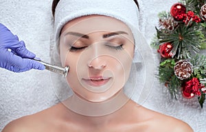 The cosmetologist makes the procedure Microdermabrasion of the facial skin of a beautiful, young woman