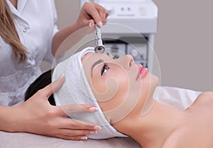 The cosmetologist makes the procedure Microdermabrasion of the facial skin of a beautiful, young woman in a beauty salon