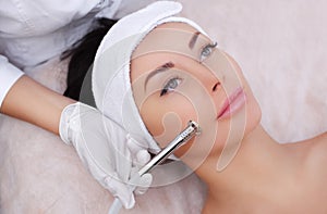 The cosmetologist makes the procedure Microdermabrasion of the facial skin of a beautiful, young woman in a beauty salon