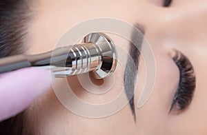 The cosmetologist makes the procedure Microdermabrasion of the facial skin of a beautiful, young woman in a beauty salon.