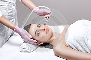 The cosmetologist makes the procedure Microdermabrasion of the facial skin of a beautiful, young woman in a beauty salon