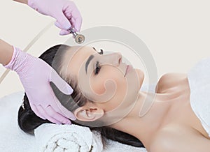 The cosmetologist makes the procedure Microdermabrasion of the facial skin of a beautiful, young woman in a beauty salon