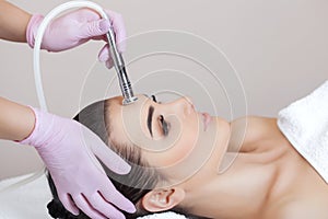 The cosmetologist makes the procedure Microdermabrasion of the facial skin of a beautiful, young woman in a beauty salon