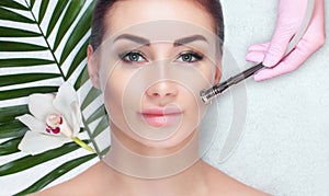 The cosmetologist makes the procedure Microdermabrasion of the facial skin of a beautiful, young woman in a beauty salon