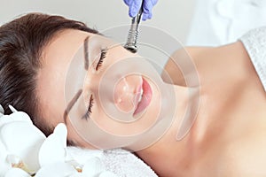 The cosmetologist makes the procedure Microdermabrasion of the facial skin of a beautiful, young woman in a beauty salon.