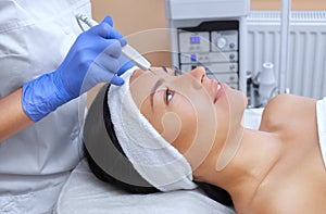 The cosmetologist makes the procedure treatment of Couperose of the facial skin of a beautiful, young woman