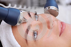 The cosmetologist makes the procedure an ultrasonic cleaning of the facial skin photo