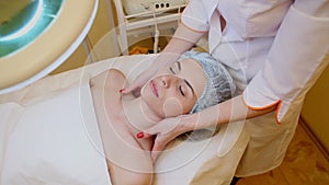 Cosmetologist makes a woman face and neck massage Spa