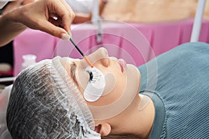 Cosmetologist making eyelash extention and correction using brush