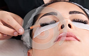 Cosmetologist making eyelash extention and correction using brush