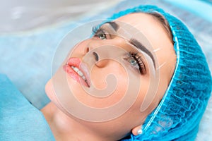 Cosmetologist making permanent makeup on woman`s face