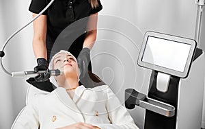 Cosmetologist performing radiofrequency facial treatment in clinic.